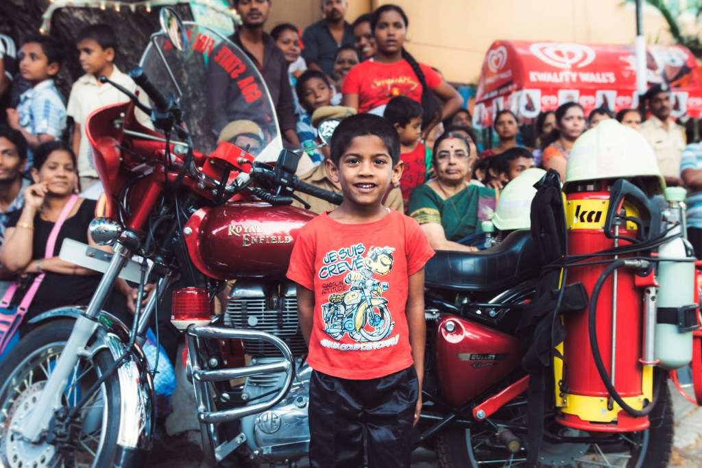 Indian boy standing in front of a Royal Enfield motorcycle belonging to the indian firefigheters in Goa during Shigmo in Panjim