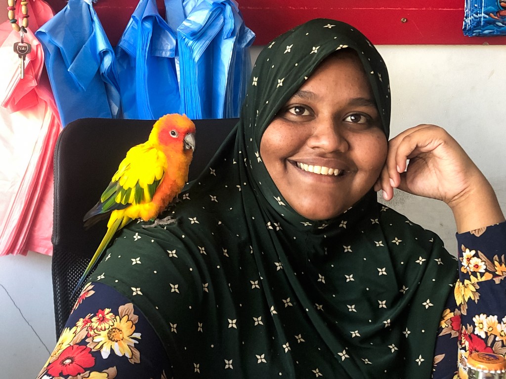 Female shopkeeper with exotic bird at the supermarket on Ukulhas, The Maldives
