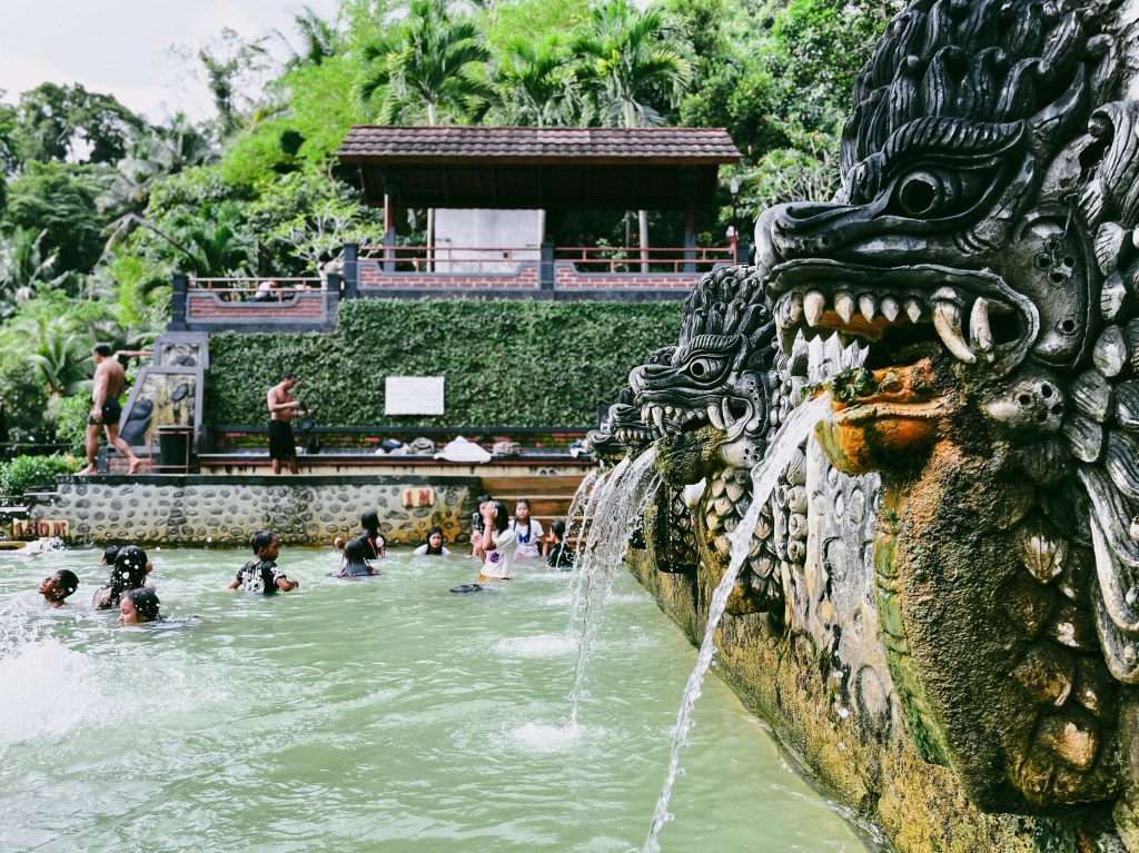 Swimming in the holy thermal bath of Banjar Sekar that's decorated with statues of dragons, Lovina, North Bali, Indonesia