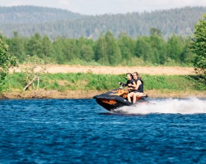 Women enjoying a water scooter ride in Torne River in Norrbotten, Sweden during the summer.