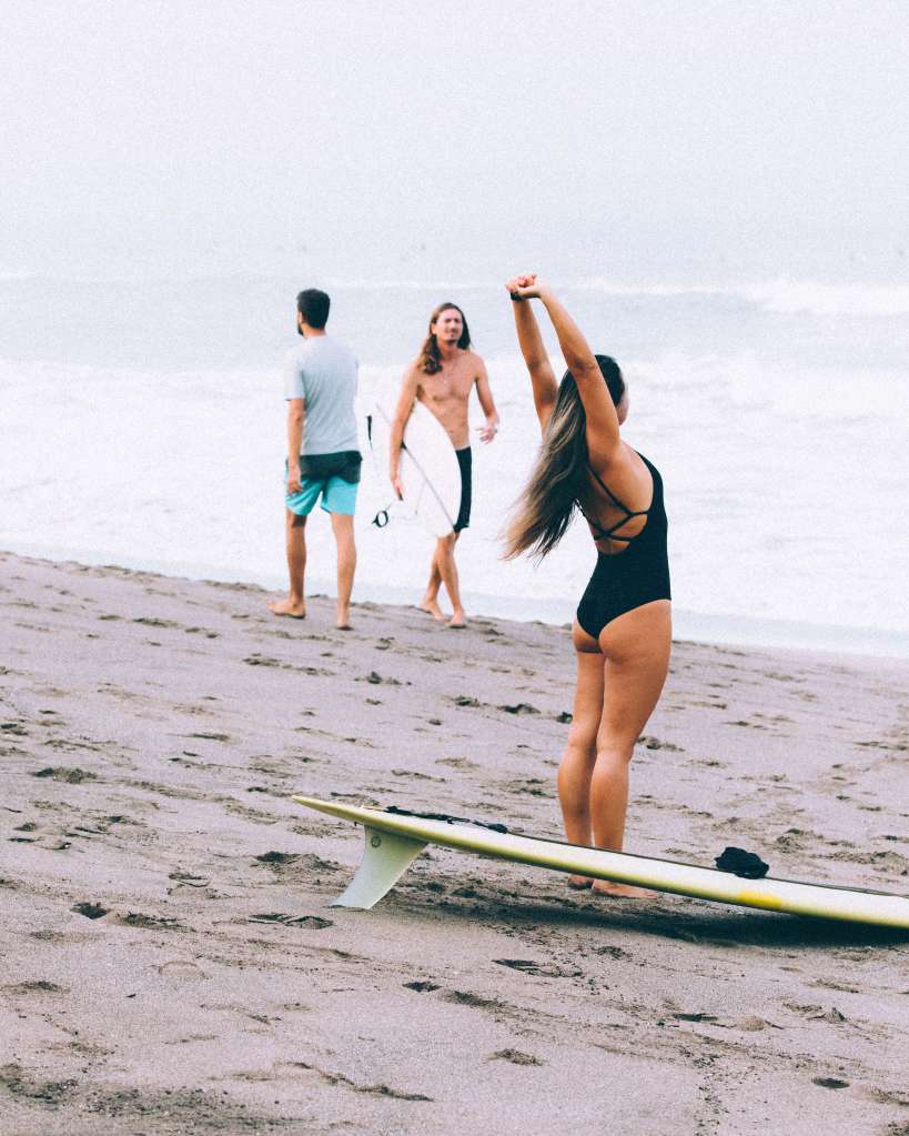 Female surfer stretching before she heads out into the surf at Batu Bolong, Canggu, Bali, April 2022