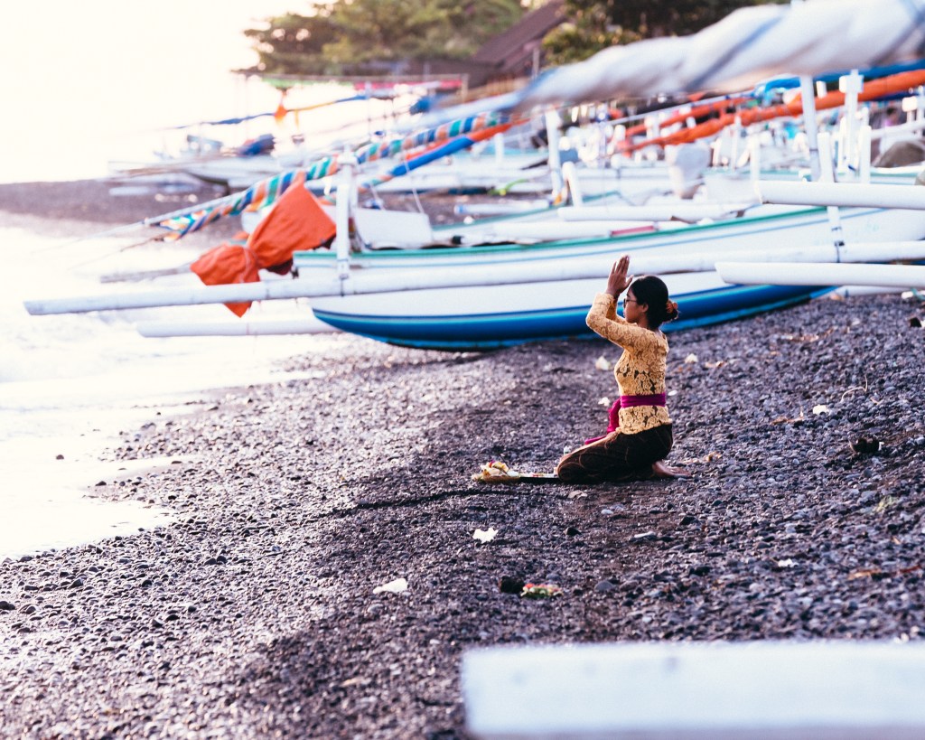Galungan morning in Amed, East Bali 2022, girl praying next to the sea.