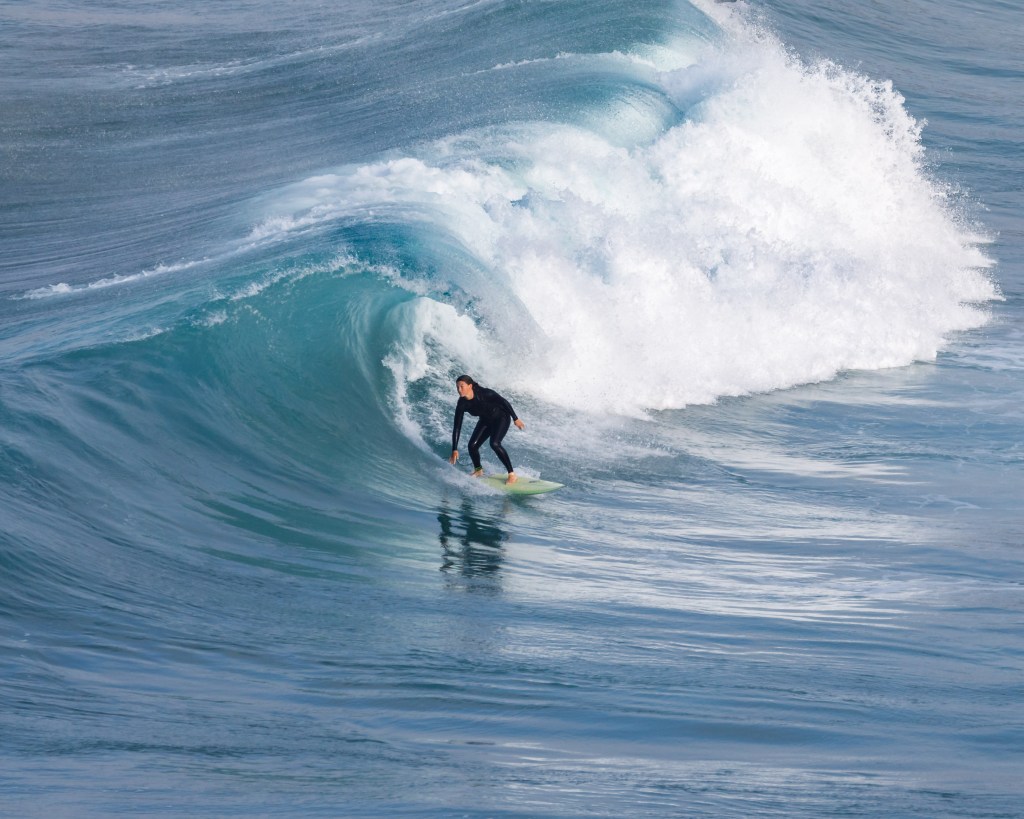 Female surfer under the lip of the wave in Praia do Tonel in Sagres, Portugal