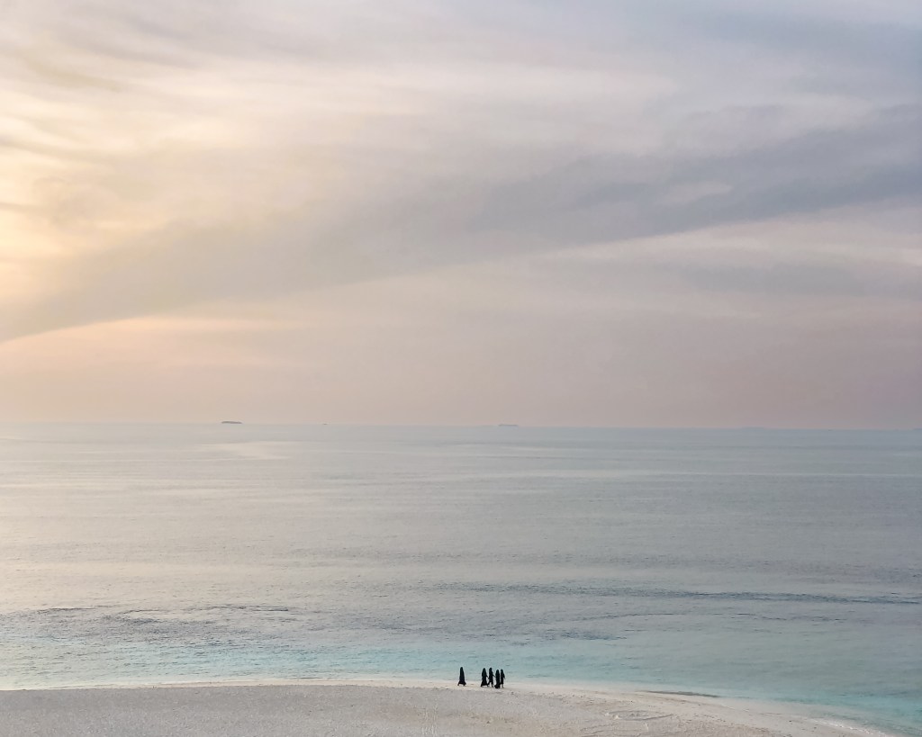 Maldivian women going out for a morning swim on the sand banks into the turquoise sea in the Maldives