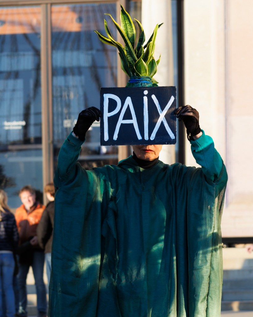 Pax, paix, peace. Female artist holding up a sign with the word peace in French in front of The National Museum in Stockholm, Sweden during Kulturnatten in April 2025.