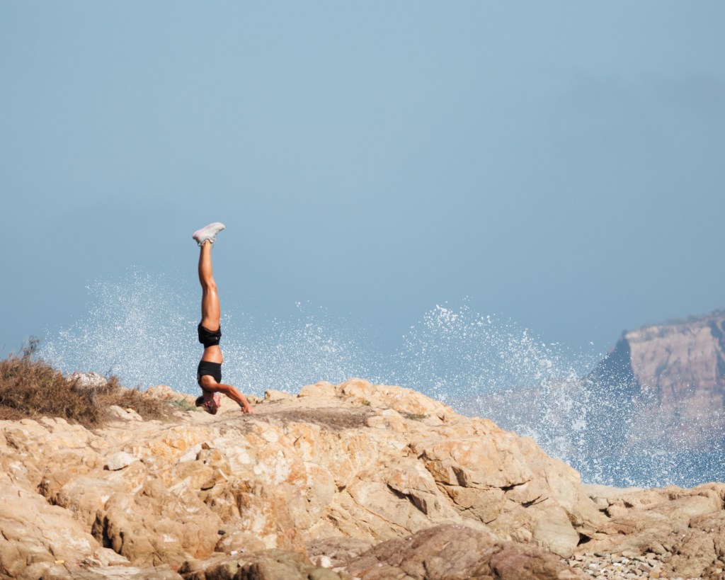 Woman doing headstand on the rocks near the beach in Playa los Pinitos, Mazaltlán, Mexico during MexiLogFest 2024. Photo is part of my contribution to the photo contest Budapest International Foto Awards 2025.