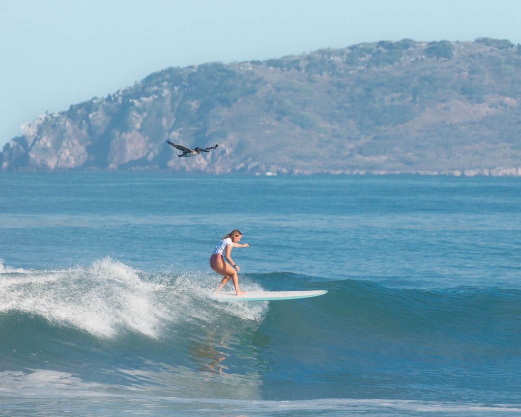 Female surfer surfing in the sea at Playa Los Pintos, Mexi Log Fest, Mazatlán, Mexico