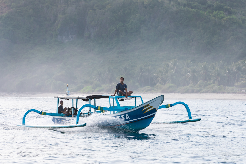 Fisherman sitting on top of a boat in the sea, Lombok, Indonesia